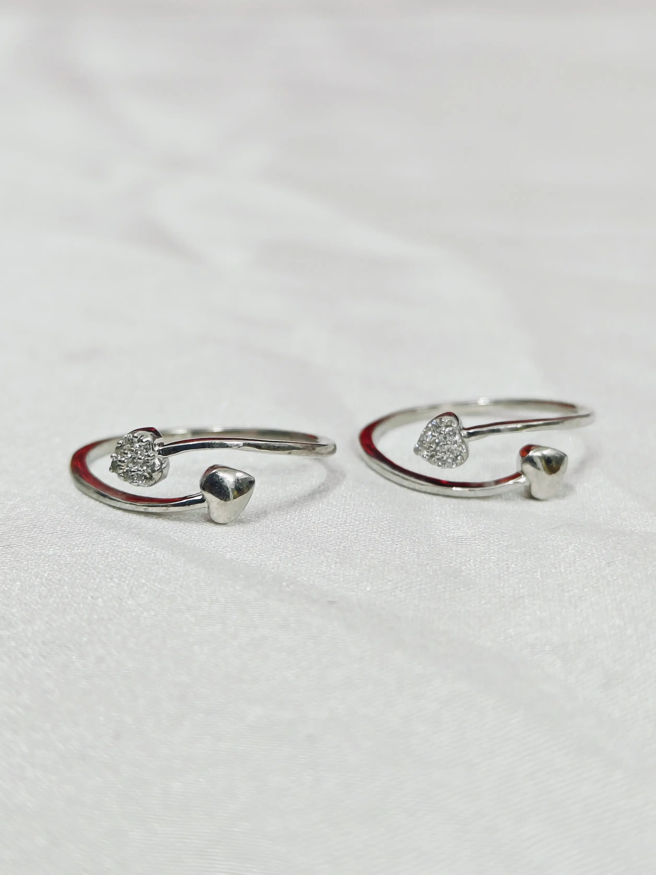 Pair of silver open rings with small stones on a light gray background